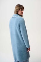 Woman wearing a light blue coat with pearl buttons on a white background