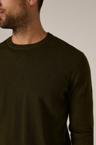 Man wearing a dark brown sweater against a neutral background
