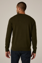 Man wearing a dark green long-sleeve shirt against a plain background