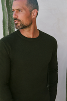 Man wearing a black long-sleeve shirt against a neutral background