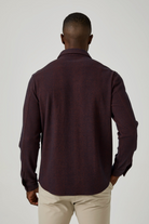 Man wearing a dark brown long-sleeve shirt against a white background