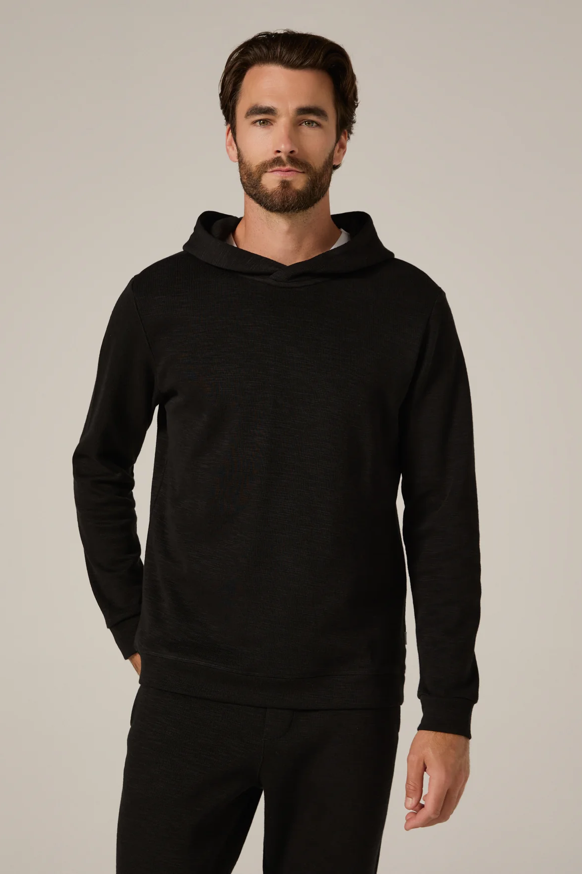 Man wearing a black hoodie against a neutral background