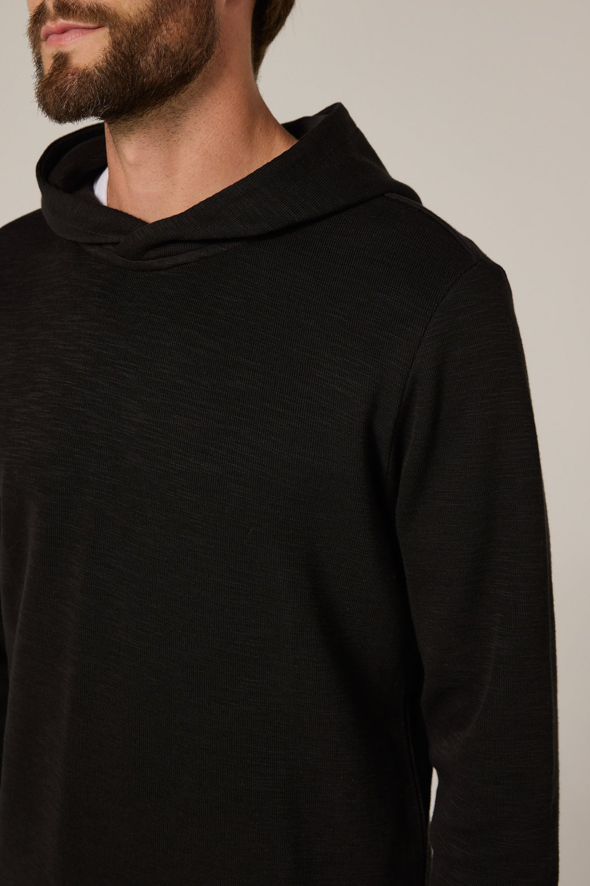 Man wearing a black hoodie against a neutral background