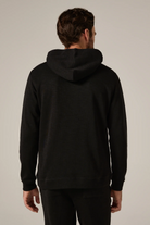 Man wearing a black hoodie from behind on a neutral background
