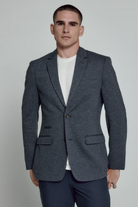 Man wearing a gray blazer over a white shirt on a plain background