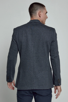 Man wearing a dark gray suit jacket on a plain background