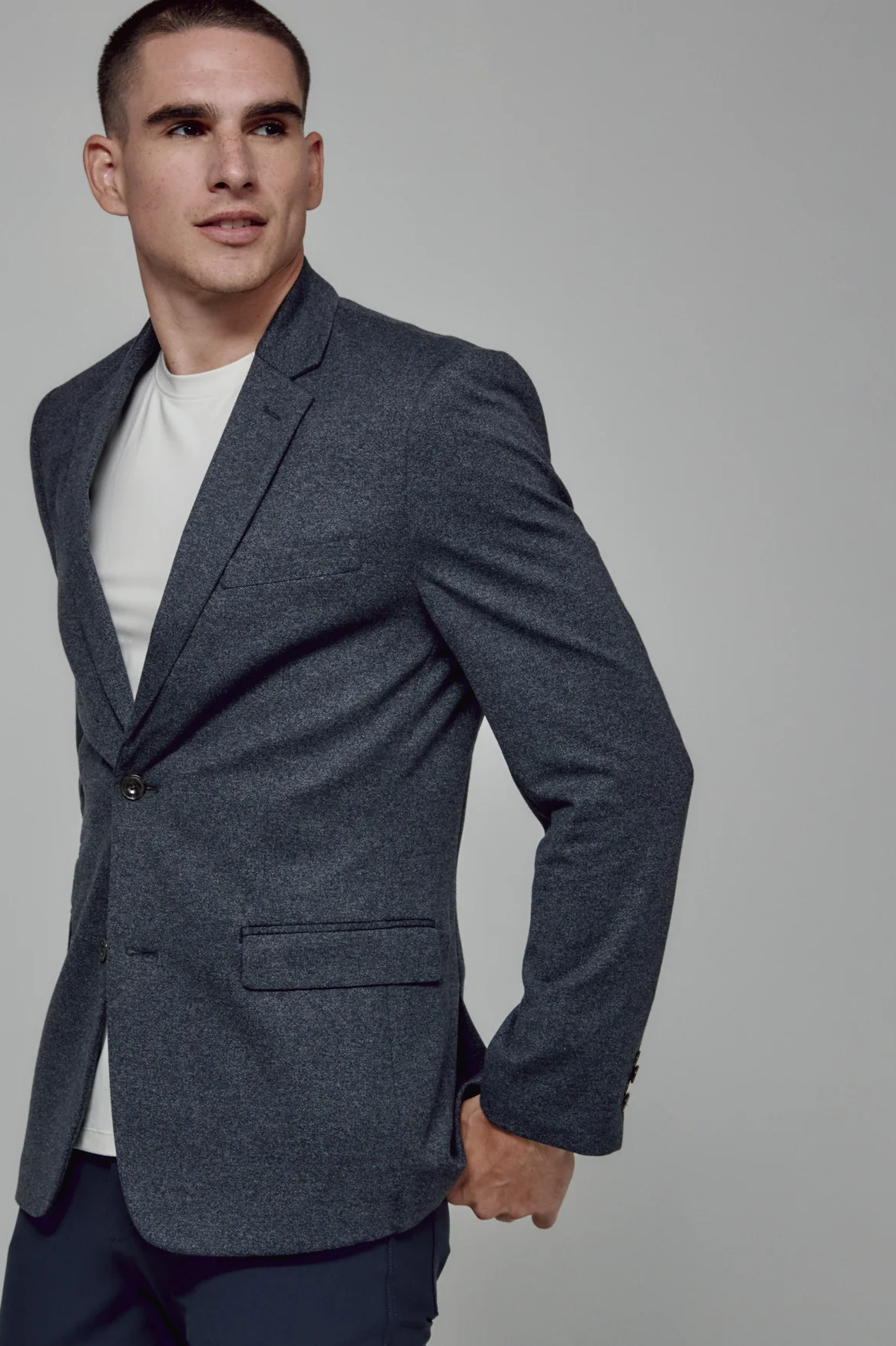 Man wearing a gray blazer over a white shirt on a plain background