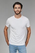 Man wearing a plain white t-shirt and light blue jeans against a gray background