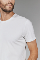 Man wearing a plain white t-shirt against a gray background