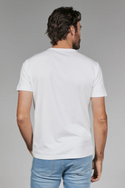 Man wearing a plain white t-shirt and light blue jeans on a gray background