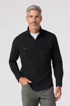 Man wearing a black button-up shirt and gray pants on a white background