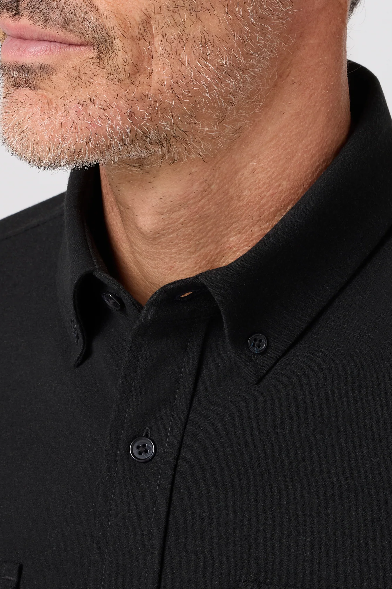 Close-up of a person wearing a black polo shirt with a neutral background