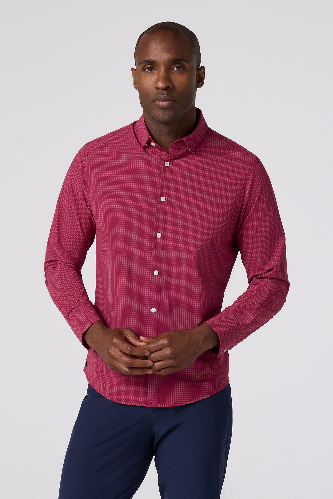 Man wearing a pink checkered shirt and blue pants on a white background