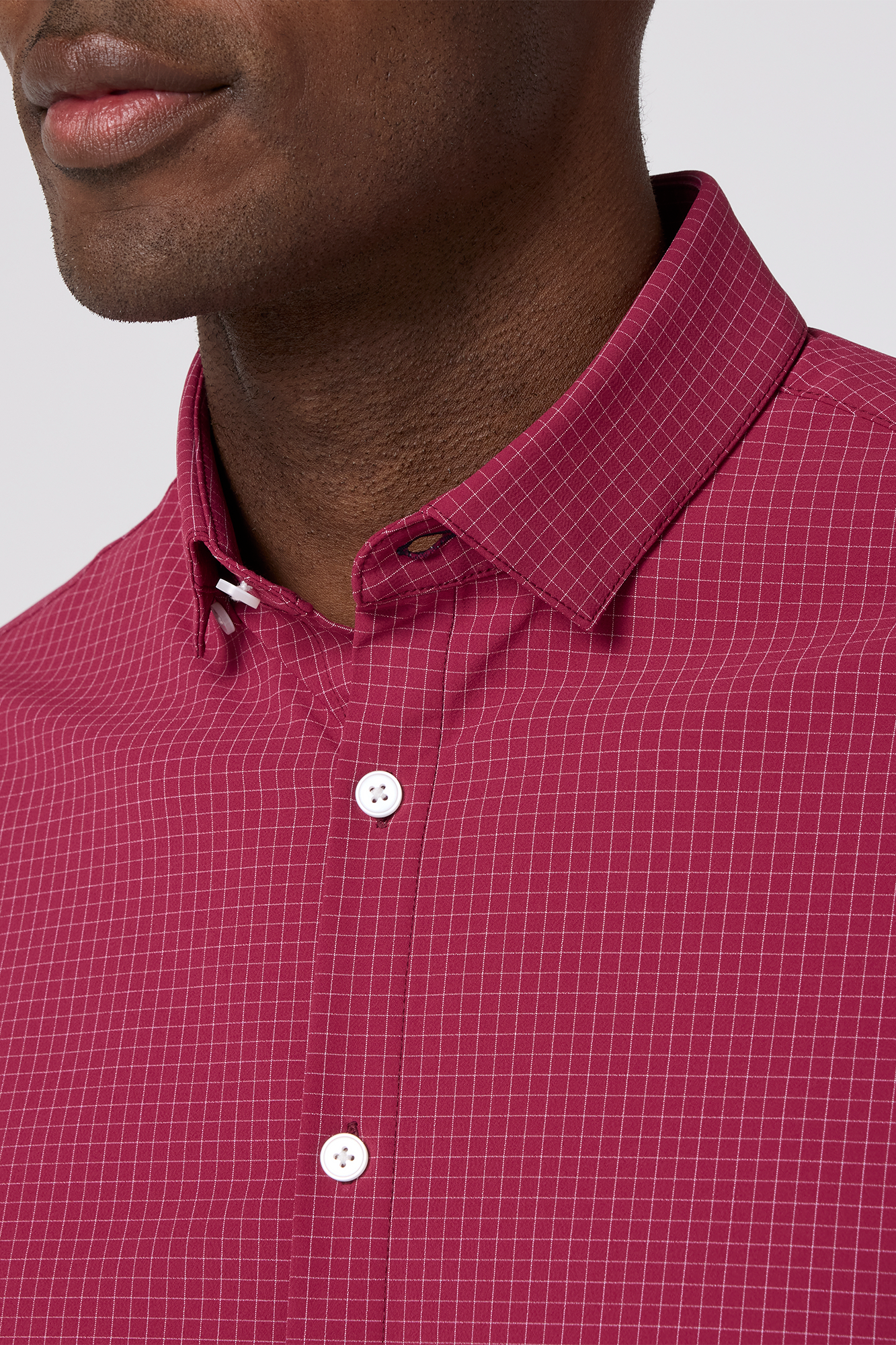 Close-up of a person wearing a red checkered shirt with a white background