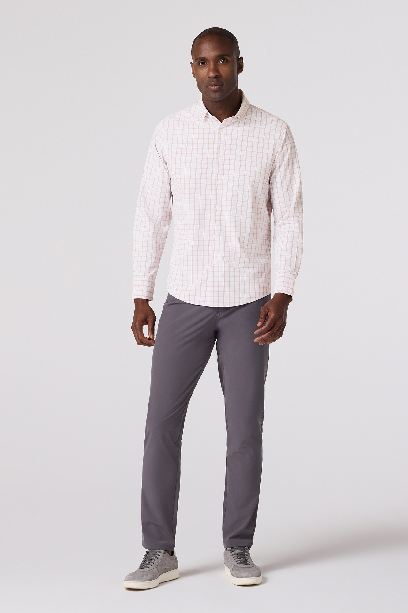 Man wearing a white long-sleeve shirt and gray pants on a white background