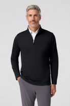 Man wearing a black quarter-zip pullover and gray pants on a white background