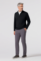 Man wearing a black quarter-zip sweater and gray pants on a white background