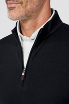 Close-up of a person wearing a black quarter-zip sweatshirt over a white shirt.