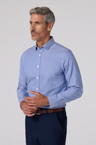 Man wearing a blue striped shirt and dark pants on a light gray background