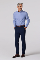Man wearing a light blue dress shirt and navy pants on a white background