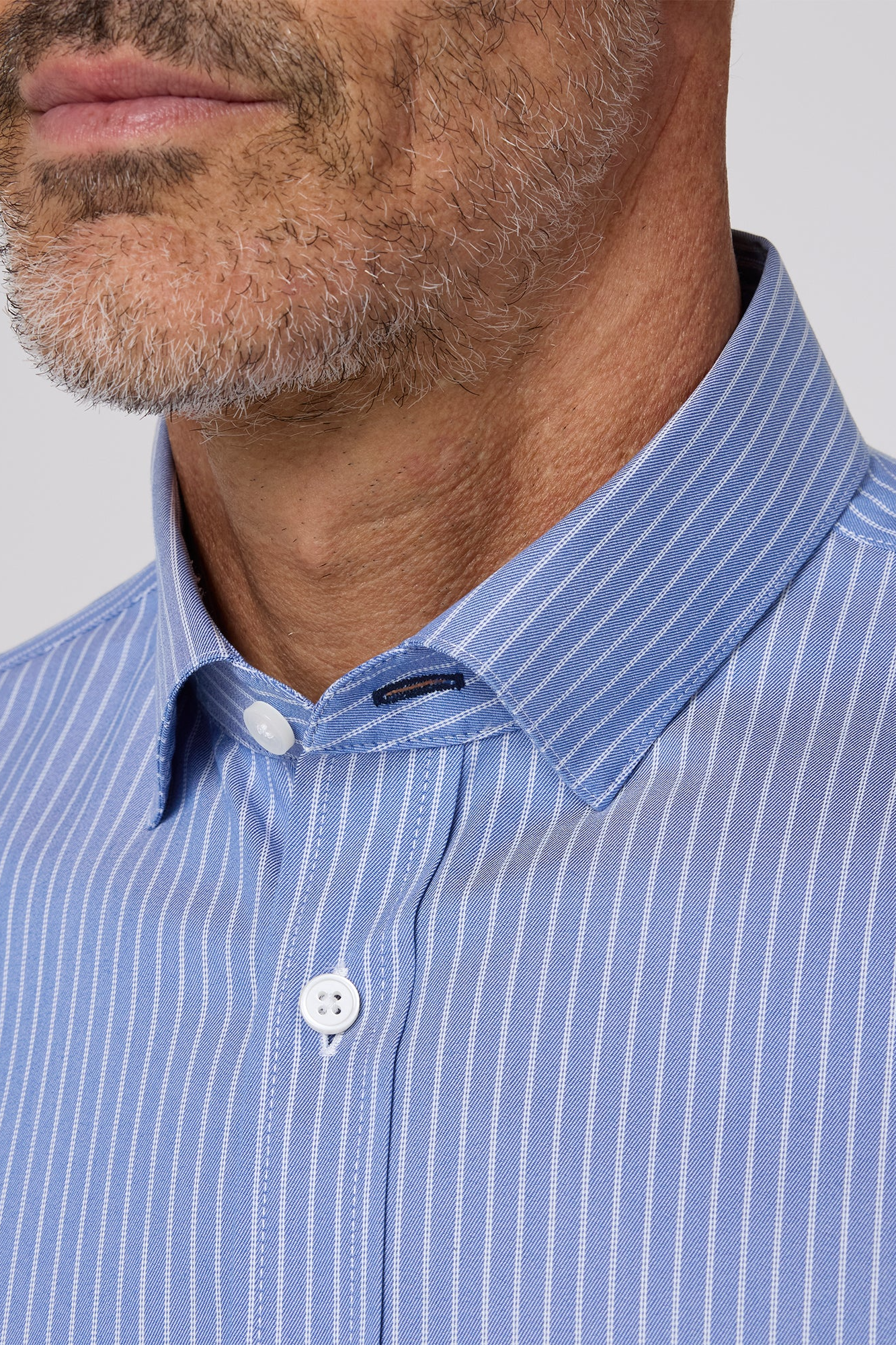 Close-up of a man wearing a blue striped shirt with a collar.