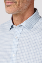 Close-up of a man wearing a light blue checkered shirt against a neutral background
