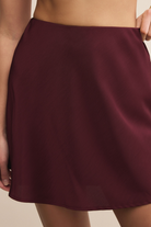 Maroon skirt worn by a person on a beige background