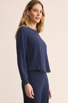 Woman wearing a navy ribbed sweater and pants on a beige background