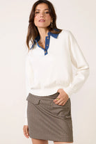 Woman wearing a white blouse with blue collar and a checkered skirt on a plain background