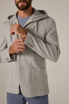 Man wearing a gray hooded jacket against a plain background