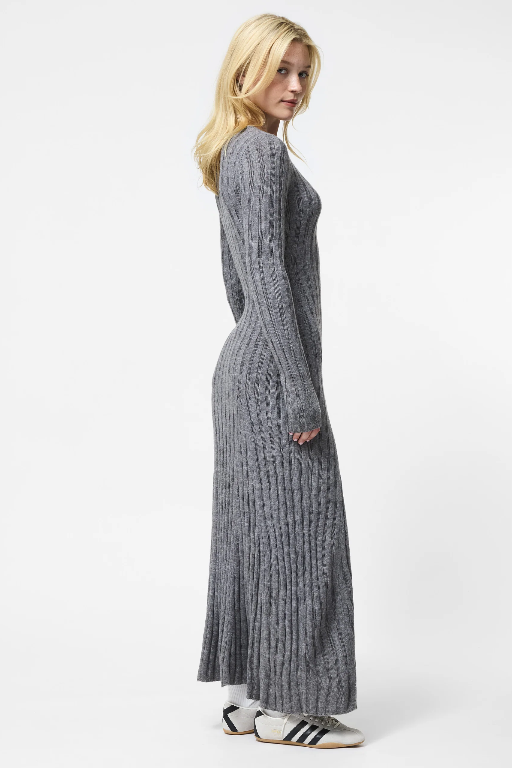 Woman wearing a long gray ribbed dress on a white background