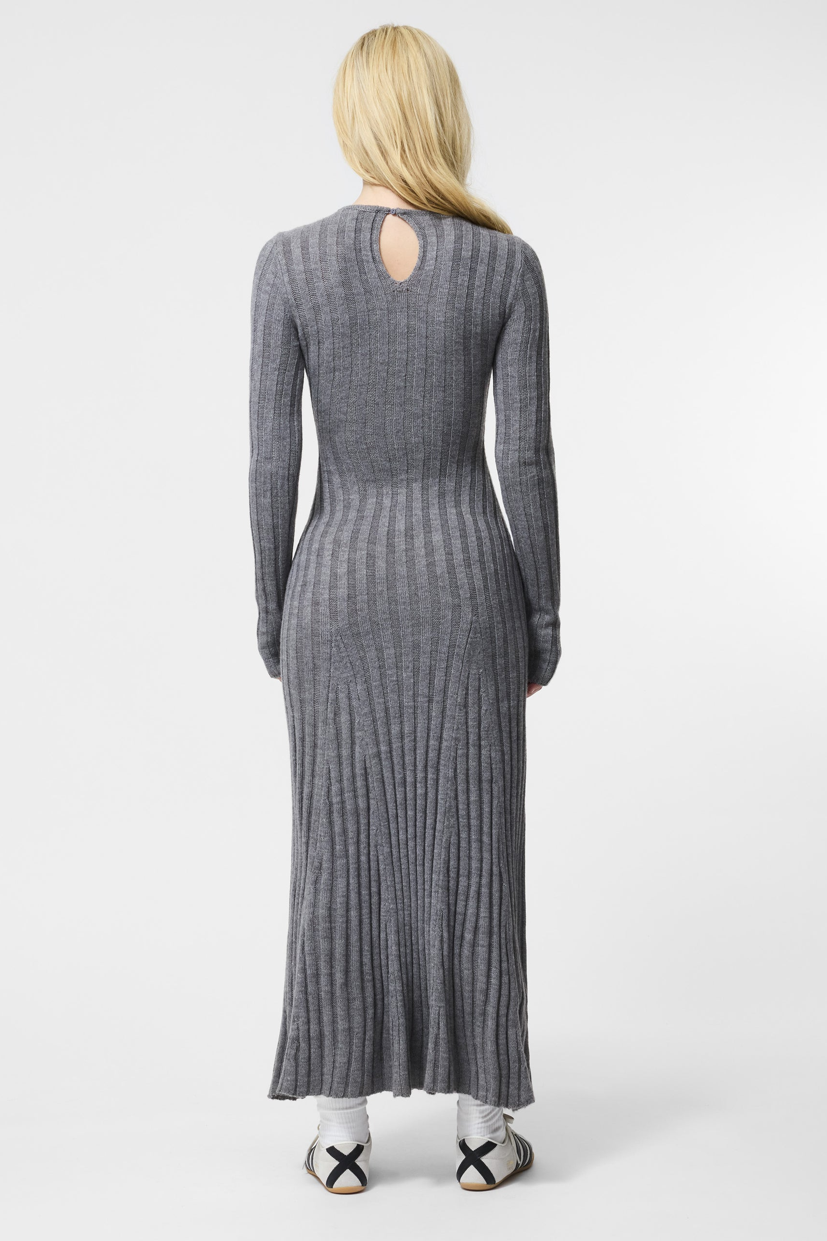 Woman wearing a gray ribbed dress with a cutout back on a white background