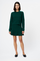 Woman wearing a green sweater and skirt set on a white background