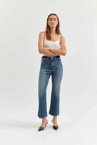 Woman wearing a white tank top and blue jeans on a white background