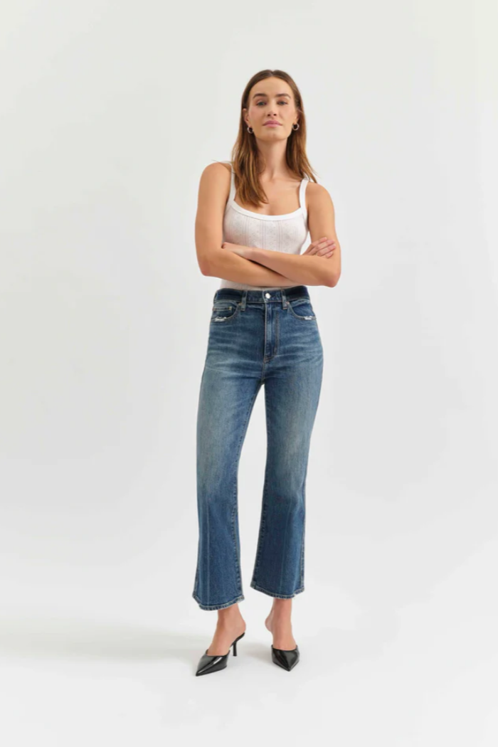 Woman wearing a white tank top and blue jeans on a white background