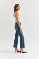 Woman wearing blue jeans and a white top on a white background