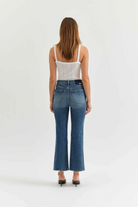 Woman wearing blue jeans and a white top on a white background