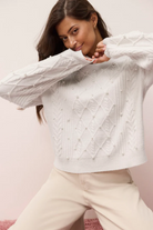 Woman wearing a white quilted jacket against a pink background