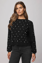 Woman wearing a black sweater with white polka dots on a gray background