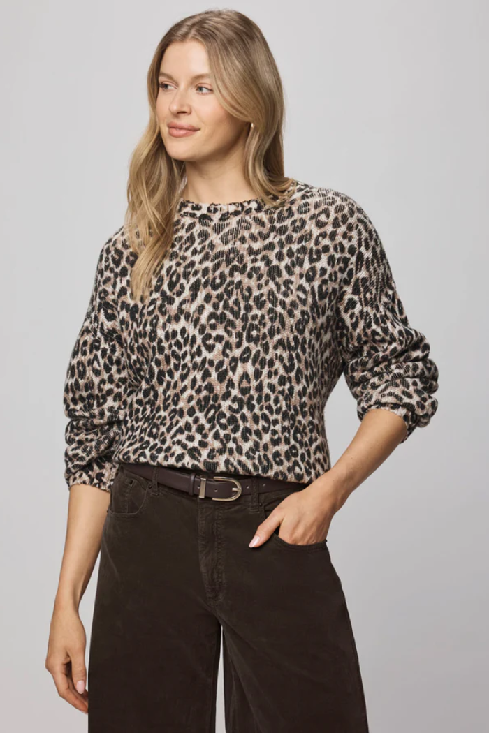 Woman wearing a leopard print blouse and black pants on a gray background