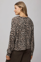 Woman wearing a leopard print top against a gray background