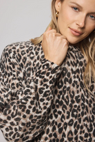 Woman wearing a leopard print sweater against a neutral background