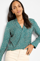 Woman wearing a green and white polka dot blouse against a light background
