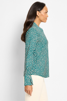 Woman wearing a green patterned blouse against a white background