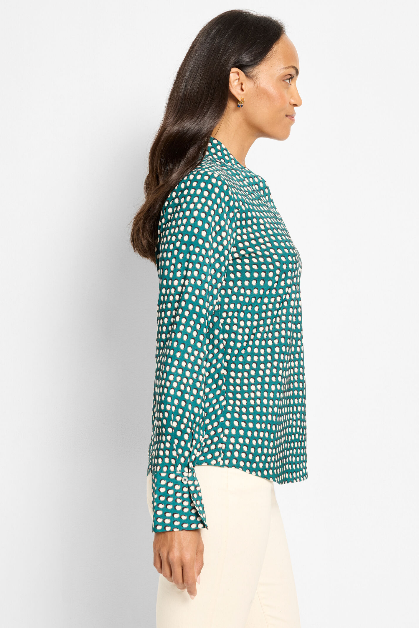 Woman wearing a green patterned blouse against a white background