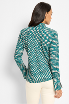 Woman wearing a green polka dot blouse against a white background