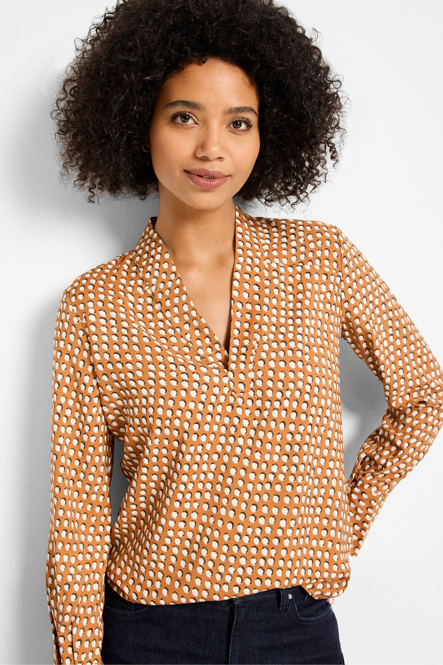 Woman wearing a patterned blouse against a plain background