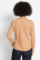Person wearing a patterned shirt with long sleeves on a plain background