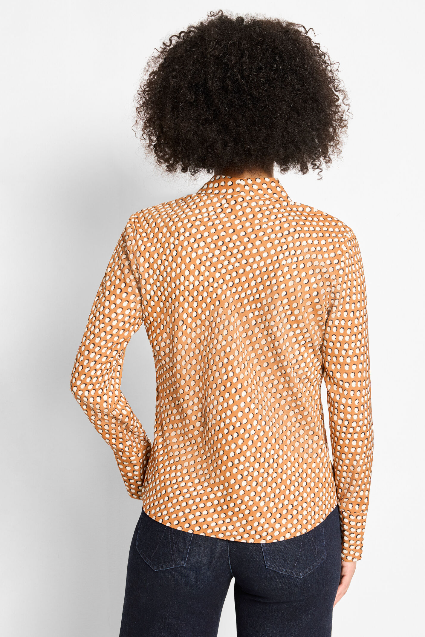 Person wearing a patterned shirt with long sleeves on a plain background