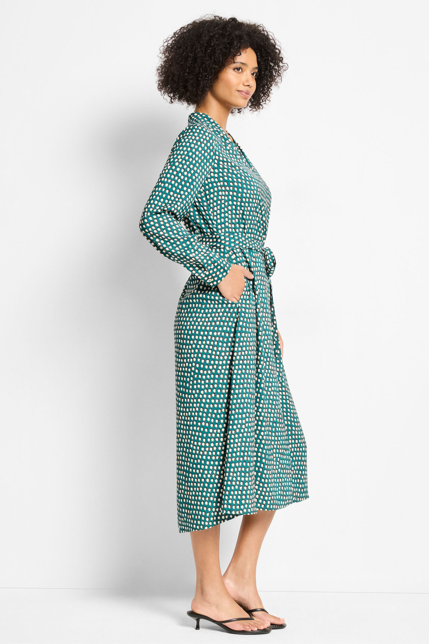 Woman wearing a green patterned dress on a white background